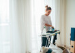 © Soloviova Liudmyla - Mindful young woman diligently ironing a light garment on an ironing board in a bright, sunlit room, practicing domestic care, household management, and finding peace in daily routine
