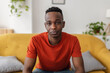 © Xavier Lorenzo - Confident African man sitting on sofa looking directly at the camera with a serious and thoughtful expression.