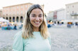 © Xavier Lorenzo - Happy young blonde woman smiling at camera standing at city street. Outside portrait of joyful beautiful girl over urban background.