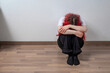 © TSViPhoto - Woman sitting on the floor with head down and arms around knees, concept of depression, anxiety and loneliness, mental health crisis and psychological distress indoors.