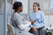 © Seventyfour - Black female nurse discussing medical information with middle aged Caucasian woman in clinical setting, nurse holding digital tablet while patient listening attentively during consultation