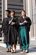 © wavebreak3 - Diverse female graduates wearing black gowns standing holding diplomas and mortarboard on plaza