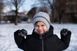 © Мар'ян Філь - Smiling child in winter coat and knit hat playing in snow with mittens up. The boy enjoys sun and snow and shows how strong he is, clenching his arms into biceps