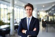© nsit0108 - Young businessman standing with crossed arms, smiling in a modern office environment
