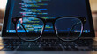 © Diana - photo of modern glasses in front of a laptop  the lenses feature a sharp vivid reflection computer programming binary code in neon blue bokeh background with copy space for campaigns hd quality