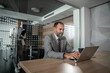 © Migma_Agency - Focused businessman typing on laptop while colleague entering office