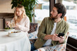 © Maria Vitkovska - Man secretly texting on smartphone, ignoring woman during restaurant date