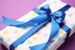 © New Africa - Wrapped gift with bow on violet background, closeup