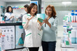 © DC Studio - Friendly pharmacist provides medical consultation to middle aged woman, explaining prescription details, medicine bottle usage, side effects and health wellness options in local dispensary.