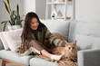 © Pixel-Shot - Pretty young woman with blanket and cute Maine Coon cat sitting on sofa at home