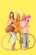 © Pixel-Shot - Young girl with bunny ears and bicycle celebrating Easter on yellow background