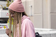 © wavebreak3 - African American teen standing on terrace with bright folders wearing pink beanie, copy space