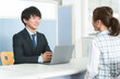 © buritora - A young Asian businessman serving a female customer at the reception desk