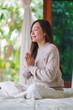 © Farknot Architect - Vertical portrait image of a woman put hands together in a prayer and meditating on the bed at home