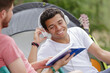 © auremar - camping man reading a book with friend