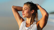 © dinatychynska - Young athletic woman with wet hair holding hands behind head on sunny beach after workout, glowing tanned skin in warm golden light, summer heat and fitness concept.
