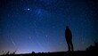 © raden - Silhouette of a person gazing at a starry night sky with meteors.