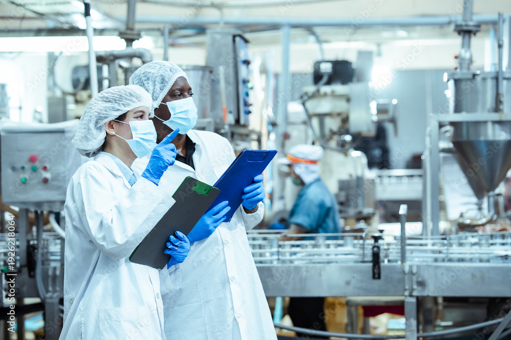 Female factory inspector wearing hairnet and gloves points toward ...