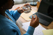 © DragonImages - Young adult Black woman holding pill and glass of water near calendar and laptop, preparing to take medication, illustrating femtech health management and daily wellness tracking