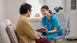 © amnaj - Asian nurse having a conversation with a senior woman at home, providing dedicated elderly care and medical support