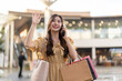 © Art_Photo - Young asian woman holding shopping bags talking on smartphone and waving hand in outdoor mall, Happy female shopper greeting friend on mobile phone, Communication, consumer lifestyle and meeting