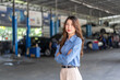 © Art_Photo - Confident asian business woman owner standing with arms crossed in auto repair shop garage, Female manager smiling at car service center, Automotive industry, mechanic and small business concept