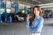 © Art_Photo - Asian business woman owner showing thumbs up in auto repair shop, Happy female manager recommending car service center, Customer satisfaction, quality guarantee and automotive industry concept