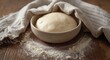 © pngking - Raw yeast dough resting in a towel-covered bowl placed on a floured surface, ideal for baking at home