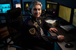 © pressmaster - Portrait of middle aged Caucasian woman wearing headset sitting at workstation operating computer in security control room, multiple monitors displaying surveillance footage and maps