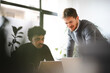© Studio Marmellata - Two men collaborate on a project, looking at a laptop screen in a modern office setting.