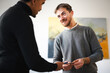 © Studio Marmellata - Two men exchange business cards in a modern office setting. One man smiles as he receives the card from the other.