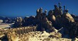 © icetray - sunlit sandstone citadel atop dunes, vast rocky bastion under deep blue sky, ornate spires and ramparts casting long shadows, winding stone bridge leading into