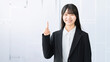 © Trickster* - 人差し指を立ててポイントを示す若い女性ビジネスパーソン, Young businesswoman pointing upward to emphasize a key point
