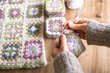 © Ina - Close up of hands joining granny squares into one fabric. Crochet project in progress. Craft process, handmade fashion creation and slow creative lifestyle concept.