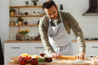 © Maria Vitkovska - Handsome Indian man wearing apron rolls out the dough in modern kitchen at home making pizza
