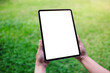 © Farknot Architect - Mockup image of a woman holding digital tablet with blank desktop white screen in the green yard