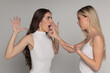 © vladimirfloyd - Studio shot of two young women friends having an argument and trying to calm down on gray background