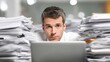 © Iuliia - Man on laptop peering over large stacks of paper. Bureaucracy and overload concept for business administration and office work.