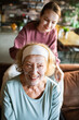 © Geber86 - Smiling senior with facial mask and young woman at home