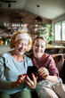 © Geber86 - Senior woman and teenage girl with facial masks using smartphone at home