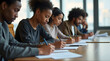 © Nathan - Diverse group of young adults focused on writing notes during a workshop session.