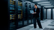© Rendara Studio - IT engineer inspecting server racks while working on laptop in enterprise data center