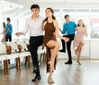 © JackF - Motivated cheerful young couple dancing vigorous lindy hop at group dance rehearsal in modern choreography studio