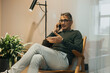 © Maskot - Full length of senior male entrepreneur talking on smart phone while sitting on chair at office seen through glass