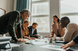 © Maskot - Group of focused business professionals examining reports in meeting at office