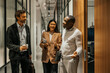 © Maskot - Male and female business entrepreneurs standing outside meeting room in illuminated office
