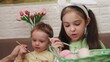 © Dilya - Happy smiling little girls and boy, kids cracking painted Easter eggs, having fun against yellow background. Concept of Easter holiday, celebration, traditions, childhood, happiness, family