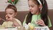 © Dilya - Happy smiling little girls and boy, kids cracking painted Easter eggs, having fun against yellow background. Concept of Easter holiday, celebration, traditions, childhood, happiness, family
