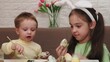 © Dilya - Happy smiling little girls and boy, kids cracking painted Easter eggs, having fun against yellow background. Concept of Easter holiday, celebration, traditions, childhood, happiness, family