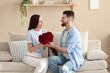 © New Africa - Man greeting his girlfriend with beautiful bouquet at home